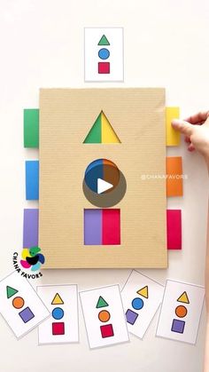 someone is holding a piece of cardboard with different shapes and colors in front of them