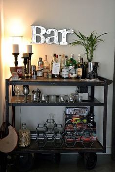 a bar cart with liquor bottles and glasses on it next to a wall mounted sign