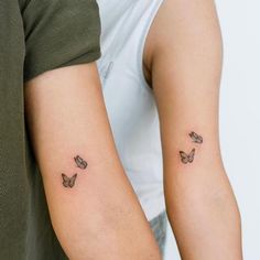 two people with matching tattoos on their arms, one has a butterfly tattoo on the other arm