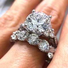 a woman's hand with a diamond ring on top of her finger and an engagement band