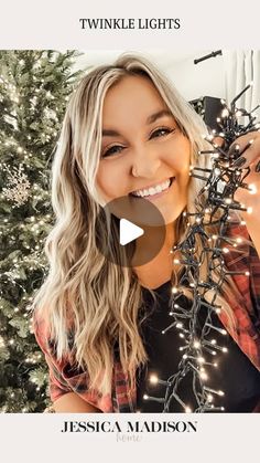 a woman smiling and holding christmas lights in front of a tree with the words twinkle lights