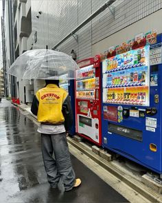 a person with an umbrella standing in front of vending machines