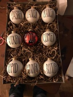 a box with six ornaments in it and the words spelled out on each ornament