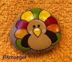 a painted rock with a turkey on it's face sitting on a carpeted floor