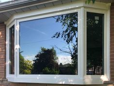 the reflection of trees and sky in a window pane on a brick house's exterior