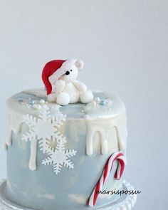 a frosted cake decorated with snowflakes and a teddy bear sitting on top