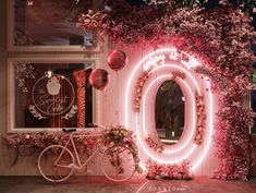 a bicycle parked in front of a building decorated with pink flowers and balloons at night