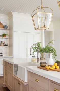 a kitchen with wooden cabinets and white counter tops, an island in the middle has lemons on it