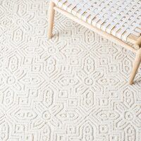 a white rug with an intricate design on the bottom, and a wooden bench in the middle