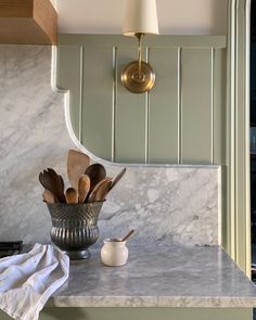 a kitchen counter with utensils in a bowl on it and a light fixture above