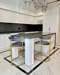 a kitchen with marble counter tops and gold accents on the island, surrounded by white cabinets