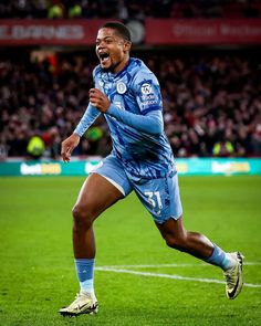 a soccer player is running on the field with his mouth open and eyes wide open