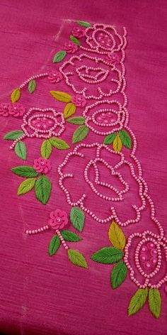 a pink table cloth with green leaves and flowers embroidered on the side, along with beads