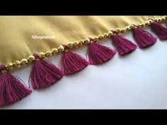 gold and pink tassels are hanging on the side of a pillow with beads