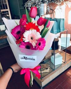 a person holding a bouquet of flowers in front of a display case with other items