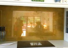 the reflection of two people standing in a living room through a glass door on top of a counter