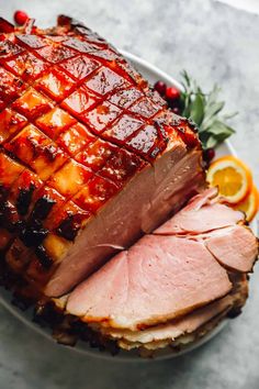 a large ham on a plate with orange slices