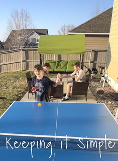 two boys are playing ping pong in the backyard