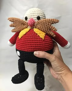 a hand holding a small crocheted stuffed animal in the shape of a bird