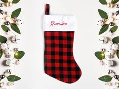 a red and black plaid christmas stocking with the word grandpa on it next to ornaments