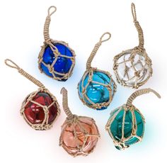 five different colored glass ornaments in wire wrapped around each other on a white table top