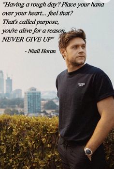 a man standing next to a hedge with a quote on it