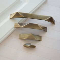 three brass drawer pulls on the floor next to a white door