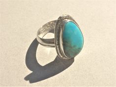 This ring features a lovely vivid blue Kingman Turquoise with a bit of olive-green Matrix. The stone is cut into a freeform teardrop and softly polished.   I set the Turquoise into fine silver onto a sterling silver; a hammered wire surrounds the setting and adds sparkle. Size of the Turquoise is about 18 x 11 x 4 mm. The 5 mm wide ring band is domed and very comfortable.  Ring size is 7 1/2. Resizing is not available. Bohemian Blue Teardrop Ring, Southwestern Blue Turquoise Teardrop Ring, Southwestern Blue Teardrop Ring, Southwestern Teardrop Blue Rings, Blue Cabochon Teardrop Ring, Blue Teardrop Cabochon Rings, Handmade Blue Turquoise Teardrop Ring, Handmade Turquoise Teardrop Ring, Handmade Teardrop Turquoise Ring