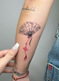 a woman's arm with a tattoo on it and a hand holding a fan