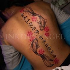 a woman's back with japanese writing and koi fish tattoos on her ribs