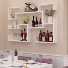 a dining room table with wine bottles and glasses on the shelves above it, in front of a wall mounted wine bottle rack