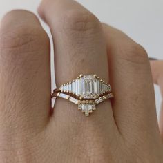 a woman's hand with a ring on it that has an emerald stone in the middle