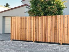 a wooden fence in front of a house with a tree on the side of it