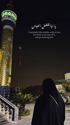 a woman standing in front of a tall tower at night with an islamic quote on it