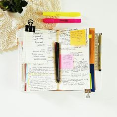 an open notebook sitting on top of a white table next to a potted plant