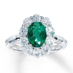 an oval emerald and diamond ring with two halos around the band, set in white gold