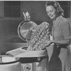 an old black and white photo of a woman ironing clothes in a machine with the lid open