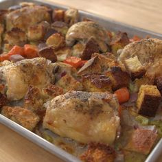 a pan filled with chicken and vegetables on top of a wooden table