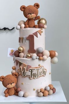 a three tiered cake with teddy bears on top and balloons all around the bottom