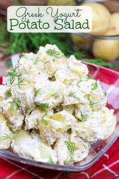 potato salad in a glass bowl on a red tablecloth with green vegetables behind it