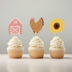 three cupcakes decorated with farm animals and sunflowers are sitting on a table