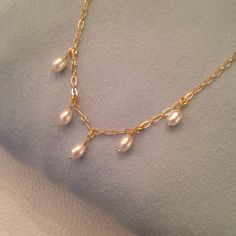 A dainty minimalist pearl necklace perfect for layering featuring five lustrous white oval freshwater pearls dangling from a delicate gold plated over brass chain. I hand wrapped each pearl and created a simple and beautiful row of cascading white pearls to hang from a glistening gold plated over brass chain. I will pack the necklace in an organza pouch and place  in a gift box with a fabric ribbon. If given as a gift, I will be happy to write a personal message for you. Please see below for des Minimalist Pearl Necklace With Delicate Dangle Chain, Minimalist Pearl Necklace With Delicate Chain, Dainty Pearl Dangle Drop Necklace, Dainty Pearl Drop Dangle Charm Necklaces, Dainty Pearl Necklace With Dangle Charm, Cushion Cut Earrings, Gold Pearl Jewelry, Pearls Jewelry, Organza Pouch