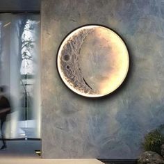 a person walking past a wall with a clock on it's face and the moon in the center