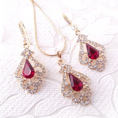 "Elegant Victorian inspired drop earrings, pendant, or necklace set with ruby red crystal center jewels bordered by swirls of pave set clear diamante. The metal is nickel-free with your choice of rose gold, silver, or gold plating. The earrings are 2\" (5 cm) long and .8\" (2cm) wide. The pendant is 1.5\" long on a chain that is adjustable from 16\"-18\" long. Ships quickly in a free gift box! I stock crystals in the full rainbow of colors and can customize this design in many colors to match yo Rose Gold Ruby Jewelry For Parties, Valentine's Day Crystal Jewelry Sets Gift, Crystal Jewelry Sets For Anniversary On Valentine's Day, Crystal Jewelry Sets For Anniversary And Valentine's Day, Crystal Rhinestone Jewelry Sets For Gifts, Elegant Jewelry Sets For Valentine's Day Formal, Formal Red Dangle Jewelry Sets, Elegant Cubic Zirconia Jewelry Sets For Valentine's Day, Red Crystal Dangle Jewelry