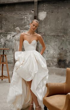 a woman in a white dress standing next to a chair