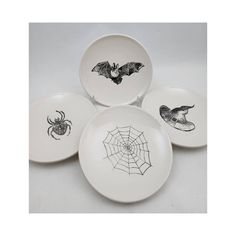 four halloween plates with bats and spider webs on them, all decorated in black ink