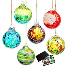 four glass christmas ornaments hanging from strings on a white background with an ornament in the middle