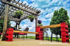 an outdoor dining area with red chairs and wooden pergoline structure in the background