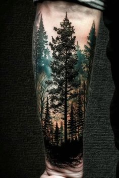 a man's arm with a forest scene on it and trees in the background