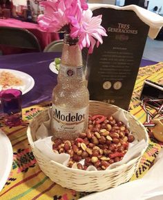 a bottle of modelo beer sitting on top of a table next to some nuts